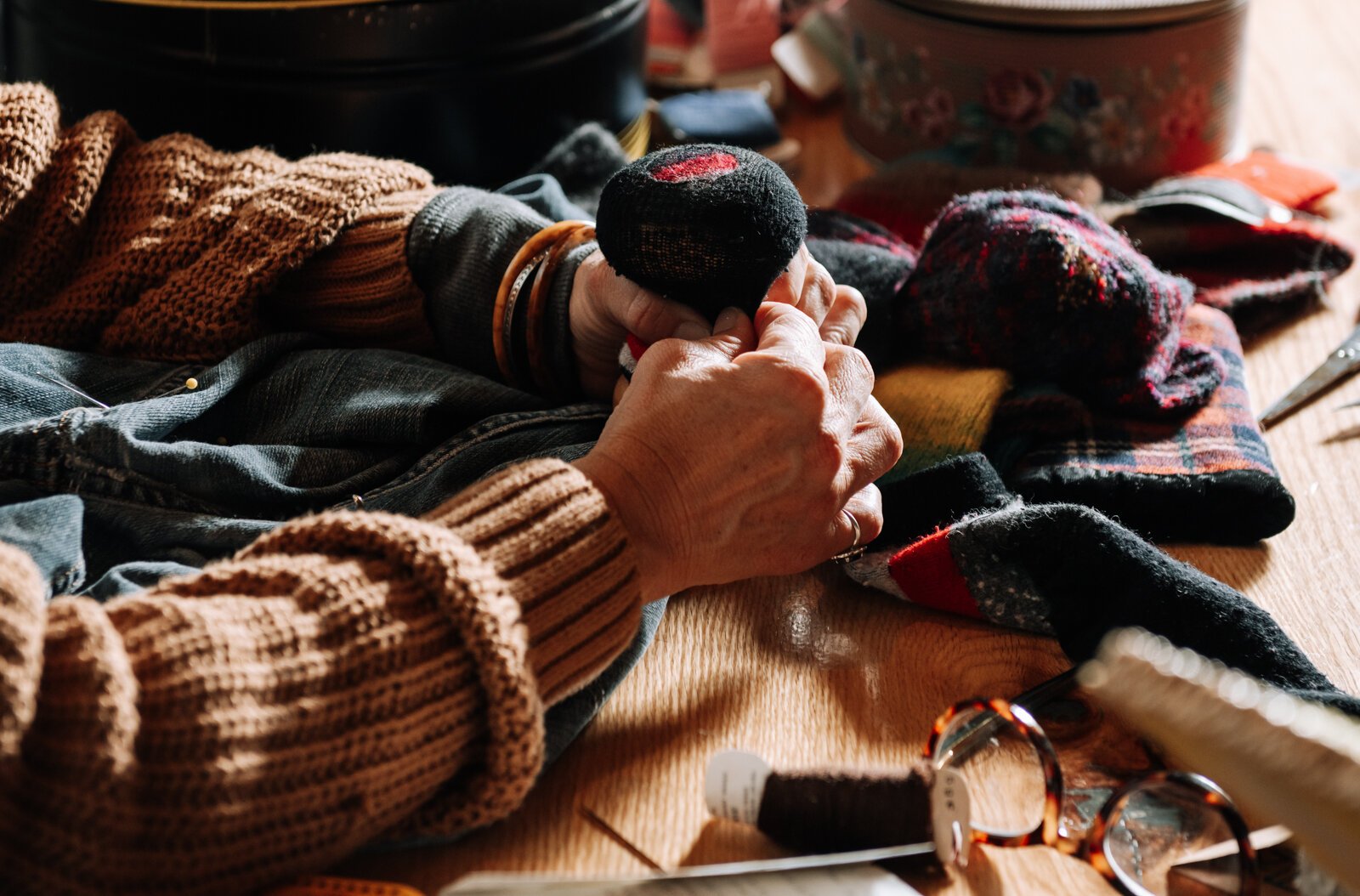 Megan Burton, who started Monday Mendings, works to fix a sock.