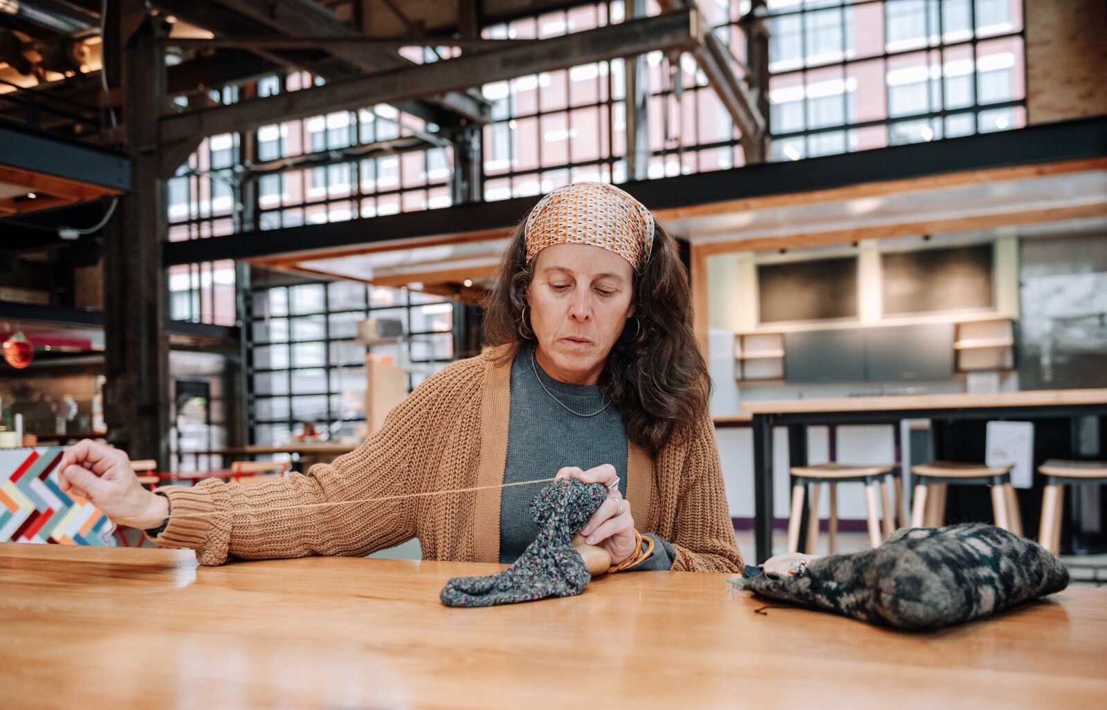 Megan Burton, owner of K1nd Goods, works on mending a sock.