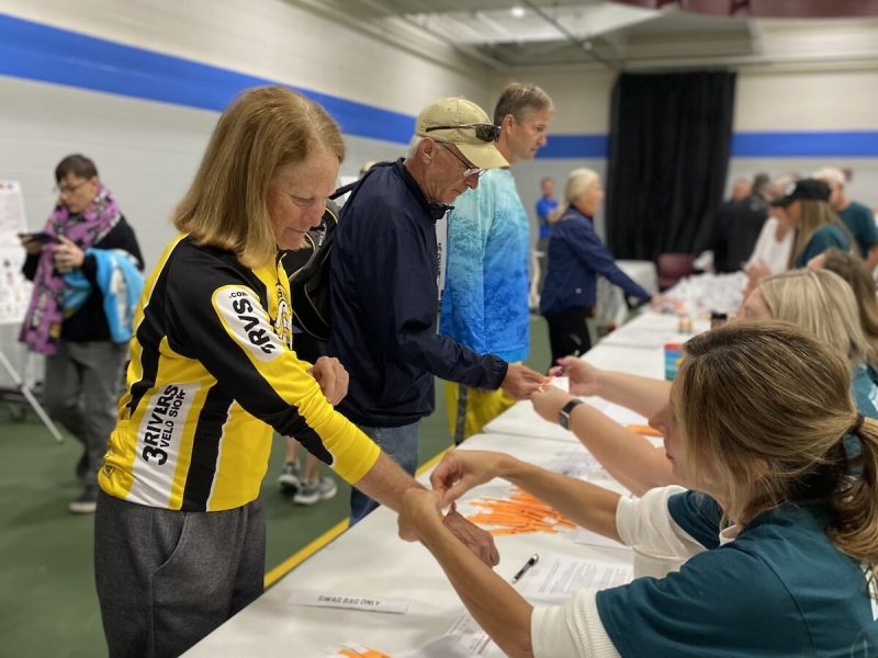 Amy Trowbridge, who works for Ford Meter Box, helps cyclists at Dam to Dam registration.