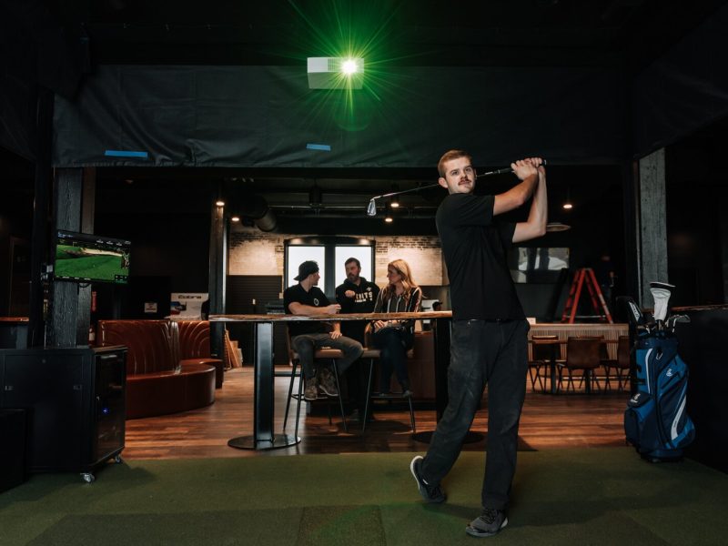 Assistant Pro Wyatt Johnson tests out a golf simulation bay at Urban Golf on the second floor at The Fairfield.