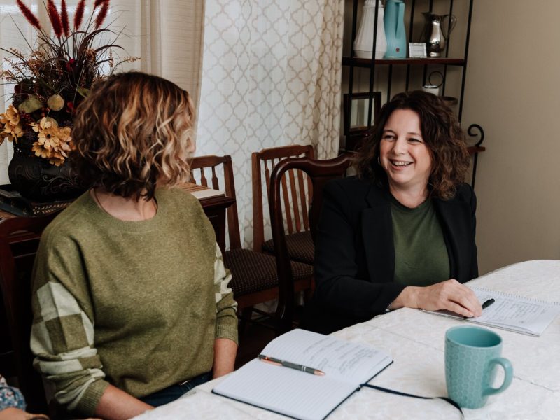 Valisha Reber, medical and social services liaison, right talks with Ann Heign, executive director, during a staff meeting at the International House office.