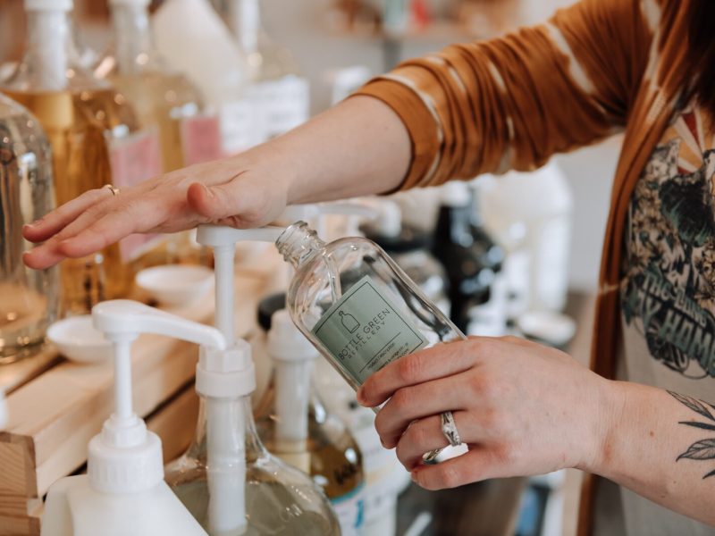 Bottle Green Refillery Owner Corinna Shoemaker refills a bottle with a lavender & lime essential oils bubble bath.