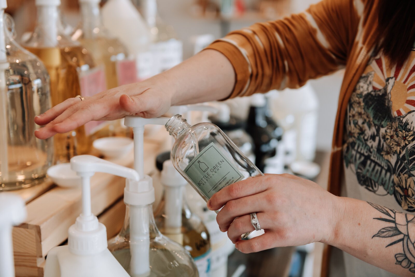 Bottle Green Refillery Owner Corinna Shoemaker refills a bottle with a lavender & lime essential oils bubble bath.
