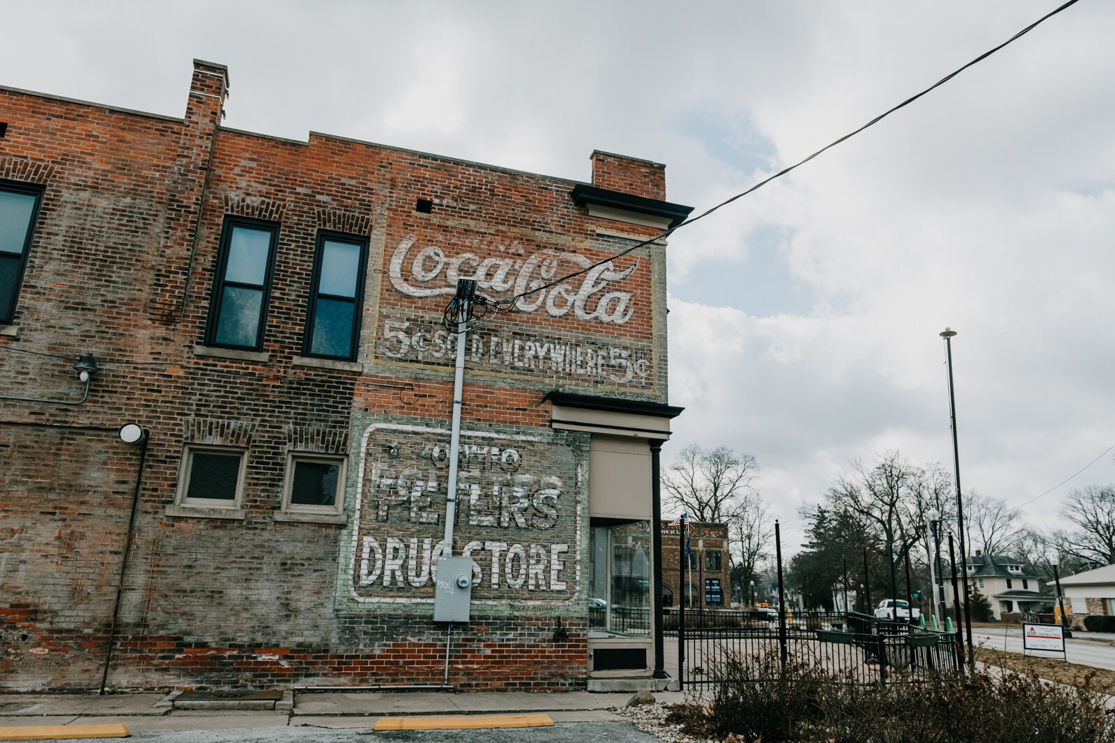 A ghost sign can be seen at 2725 Broadway, which used to house Trubble Brewing. The sign reads Otto Peters Drugstore and contains an advertisement for Coca Cola.
