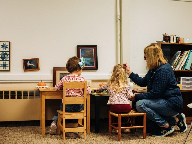 A guide (teacher), works with children on classroom activities.