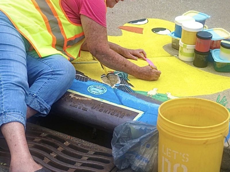 Joan Means paints a new mural on the corner of Calhoun Street and E. Masterson Avenue during Open Streets Fort Wayne.