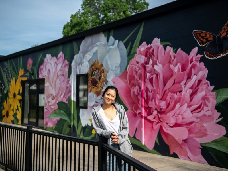 Detroit-based artist Louise 'Ouizi' Jones paints a mural in downtown Roanoke inspired by common Indiana flowers, including peonies and black-eyed Susans.