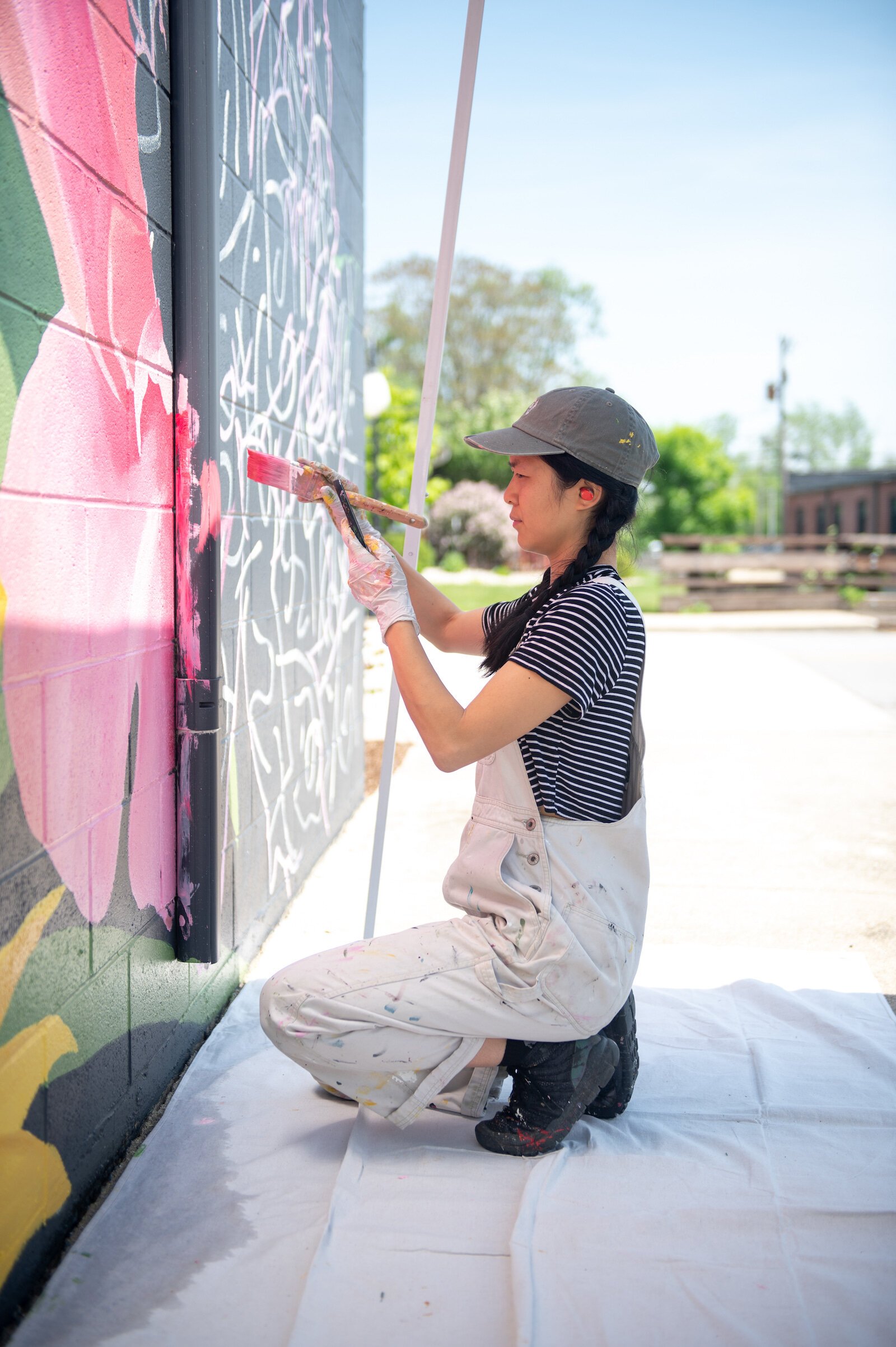Detroit-based artist Louise 'Ouizi' Jones paints a mural in downtown Roanoke inspired by common Indiana flowers, including peonies and black-eyed Susans.