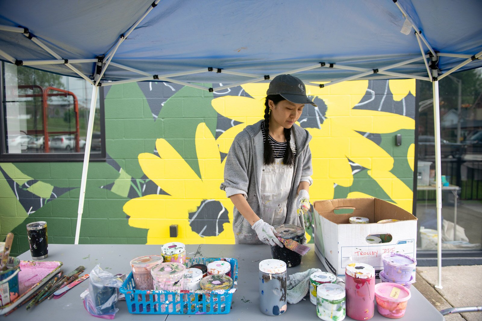 Detroit-based artist Louise 'Ouizi' Jones paints a mural in downtown Roanoke inspired by common Indiana flowers, including peonies and black-eyed Susans.