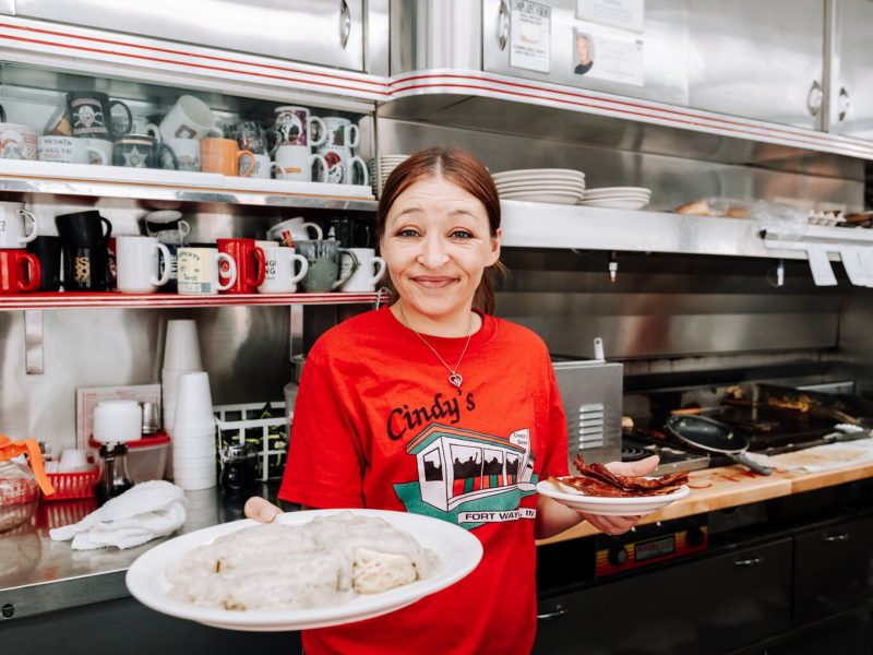 Server Sheila Williams serves a plate of country sausage gravy and biscuits with a side of bacon at Cindy's Diner, 230 W. Berry St.