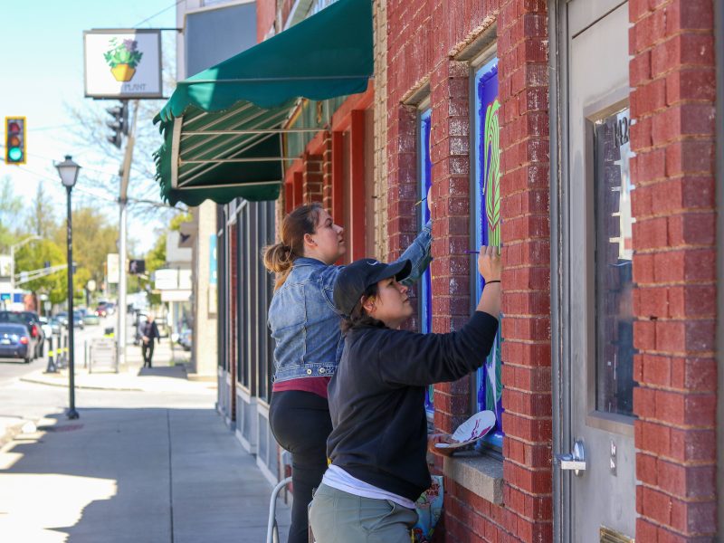 Sisters Cecilia Dunifon and Olivia Perez work on a "blooming" mural on Wells Street.
