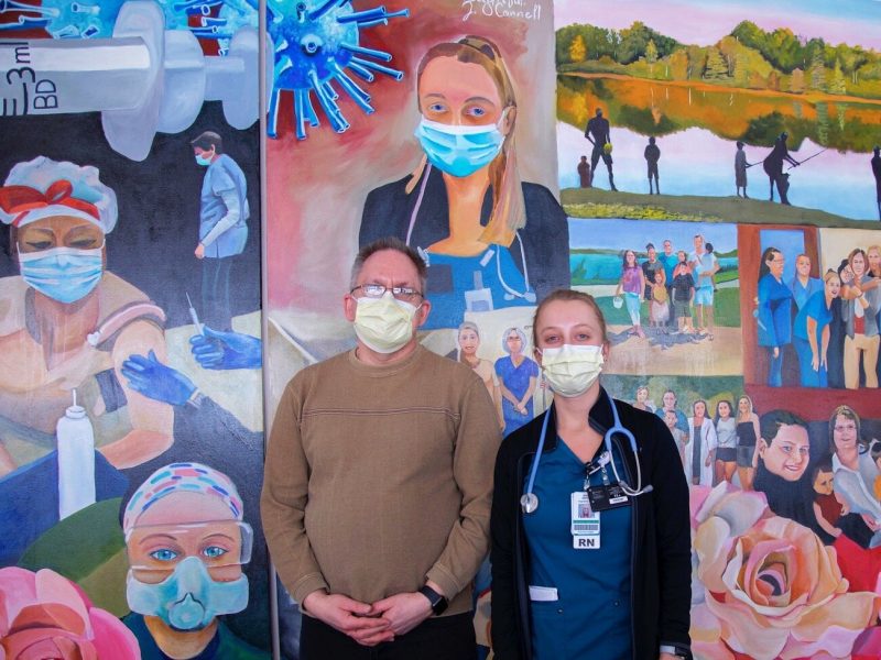 Parkview RN and artist Jason O’Connell, left, stands with one of his coworkers featured in his mural at Parkview Heart Institute.