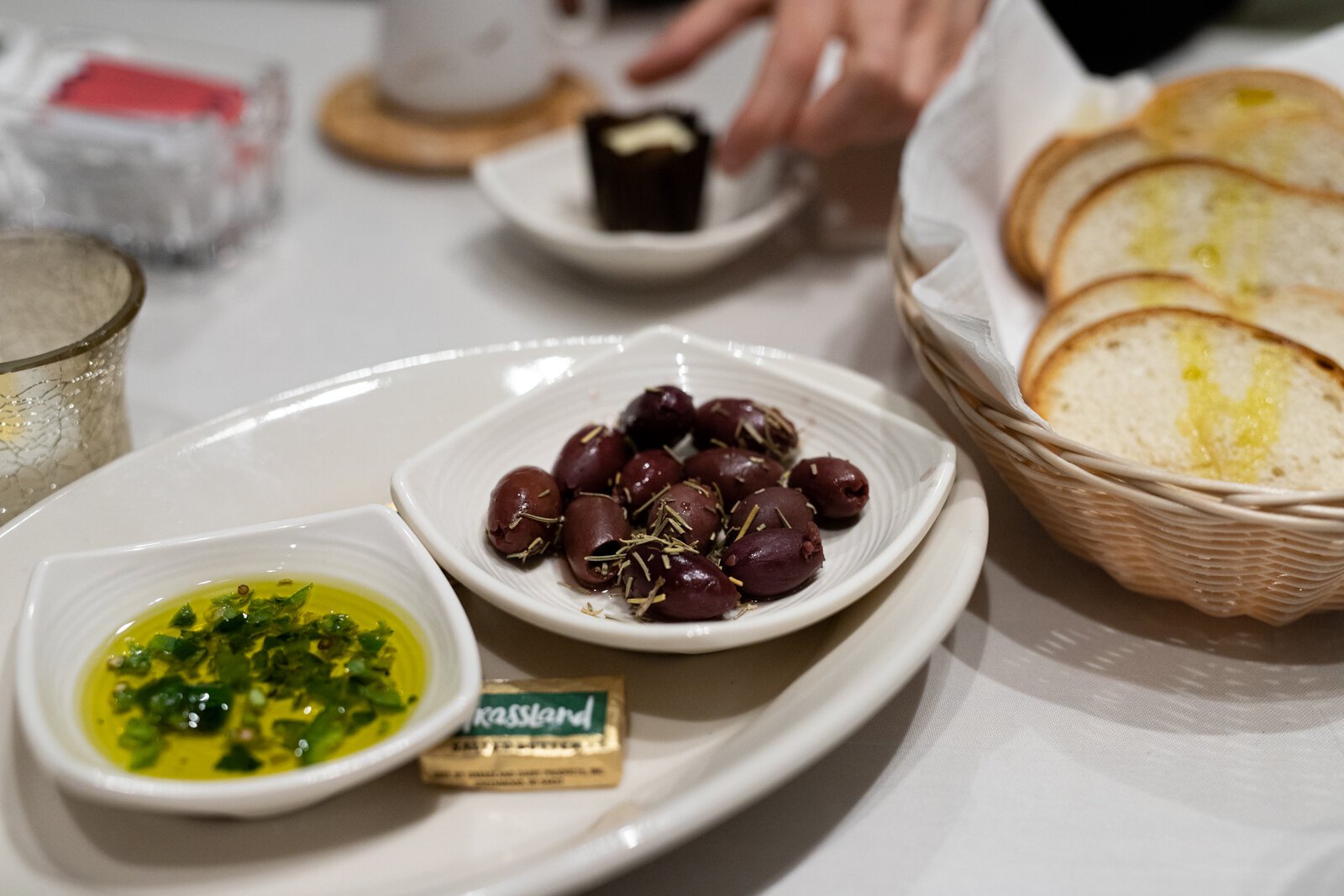 A small saucer of marinated kalamata olives and rosemary accompanies the bread and oil for a snack that’s rich and gets you salivating for your meal to come.