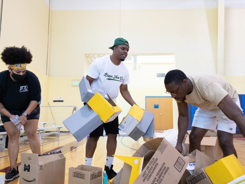 From right: Bigger Than Us volunteers Carmen Lowe and Lorenzo Holder help CEO of BTU Jerrell Holman with cleaning up boxes before the start of the Book Bag Giveaway at Renaissance Pointe YMCA, 2323 Bowser Ave. on August 7, 2021.