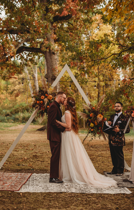 Groom Samuel Silver kisses bride, Taylor Hollister, as Aaron Robles officiates. Photo by Roots of Life Photography-Fort Wayne.