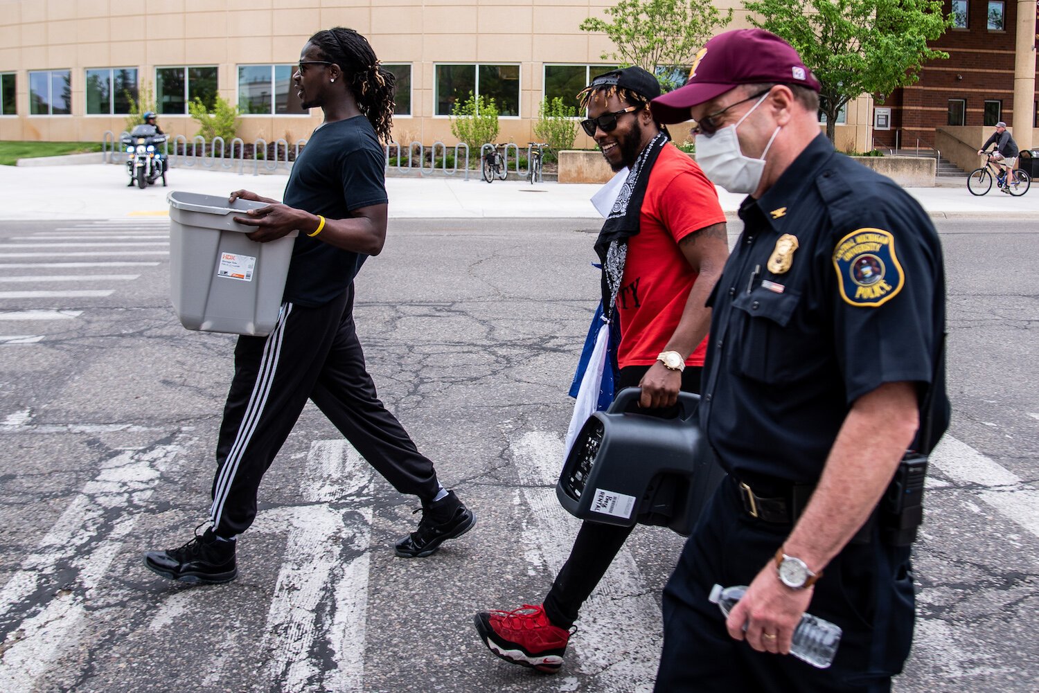 Trokon Jayqua, left, and Tim Crosby, both of Mount Pleasant, carry equipment to a police officer’s vehicle before an event to protest the death of George Floyd.