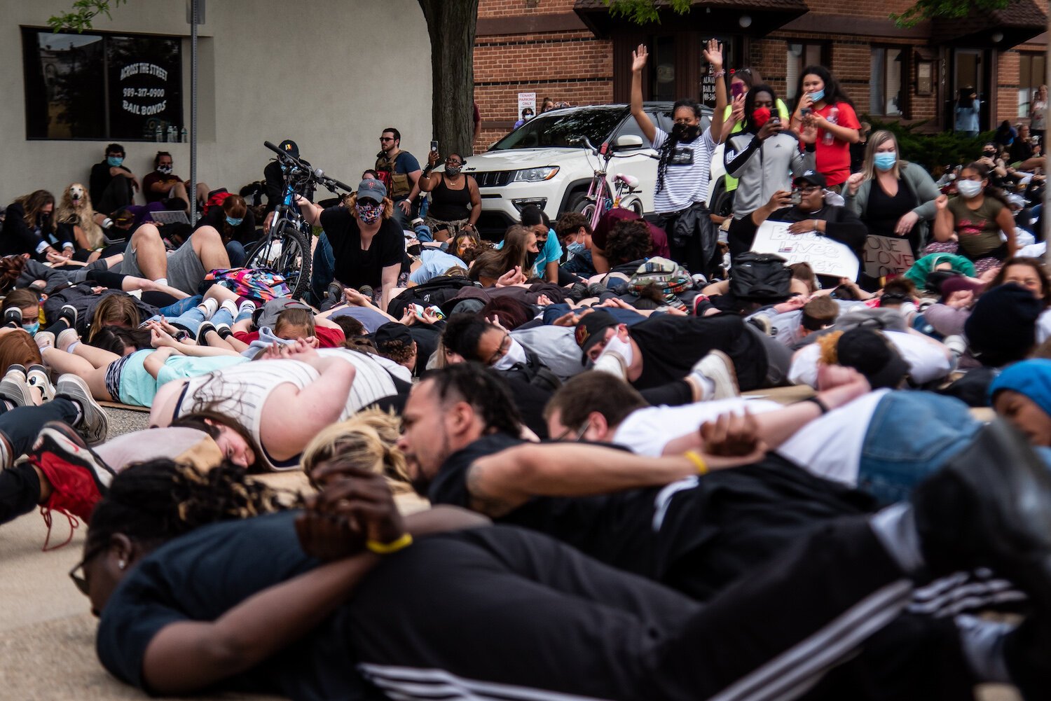 Protestors lie on the ground and chant, “I can’t breathe,” for nine minutes while others document during an event to protest the death of George Floyd outside the Isabella County Sheriff’s Office in Mount Pleasant, MI.
