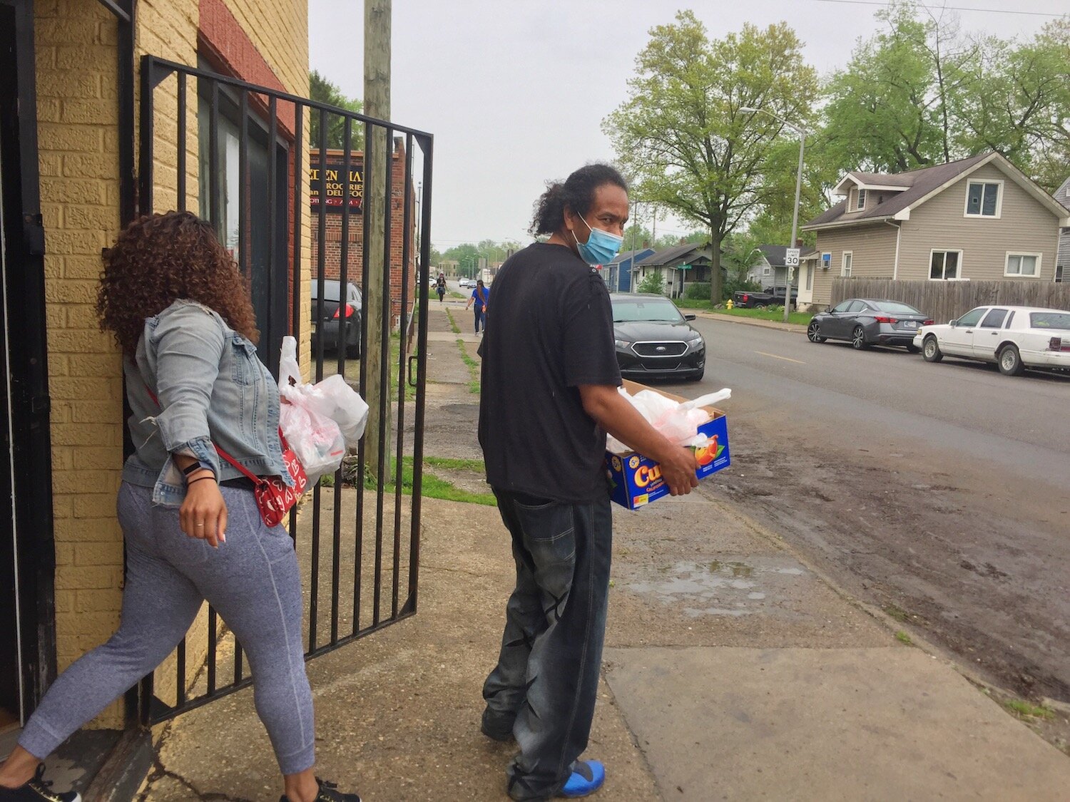 Ty Simmons, right, carries boxes of to-go meals to deliver to residents stuck at home.