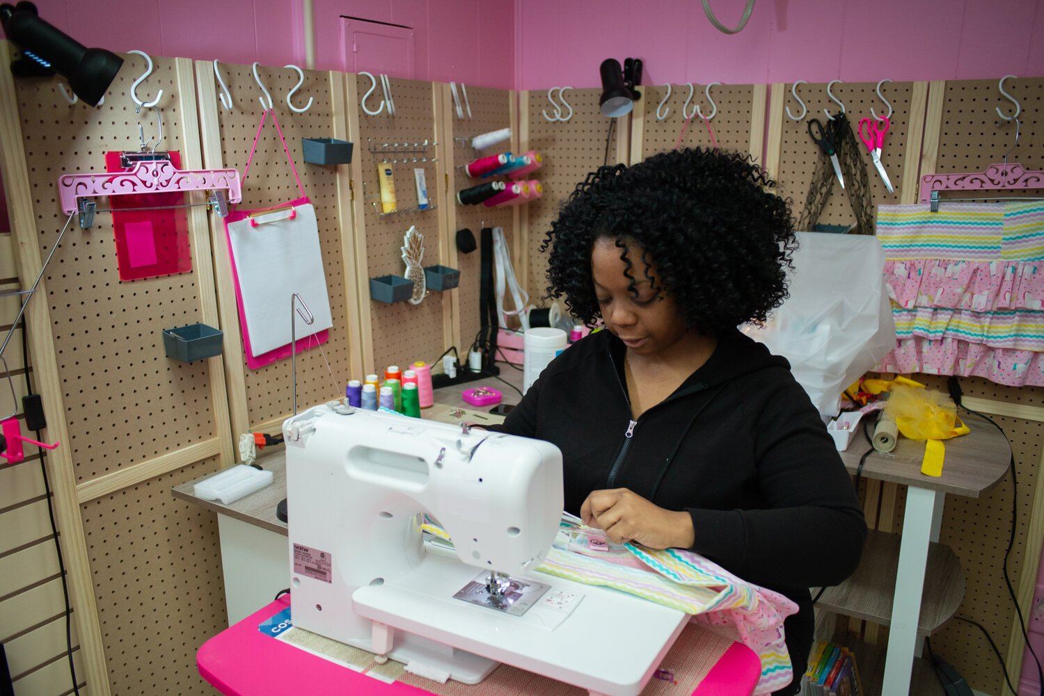 Pinky finishes the waistband on a garment at her shop.