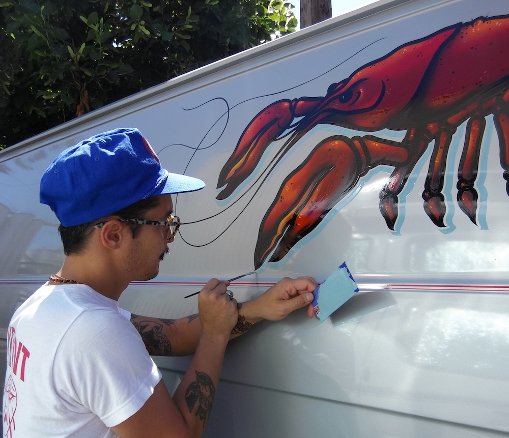 Justin paints a lobster on the side of the van.
