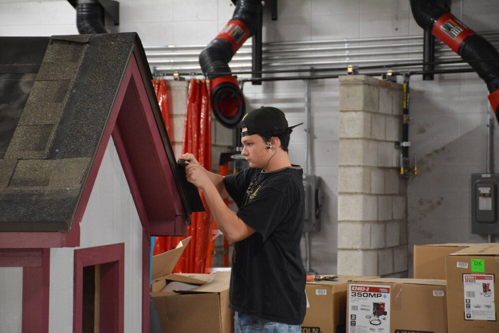 A Garrett High School student works on a playhouse they plan to auction.