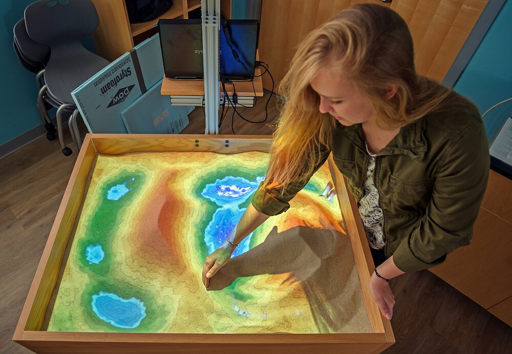 The Lilly Center's Learning Lab has an augmented reality sand table where students can push the sand around, changing the topographical map.