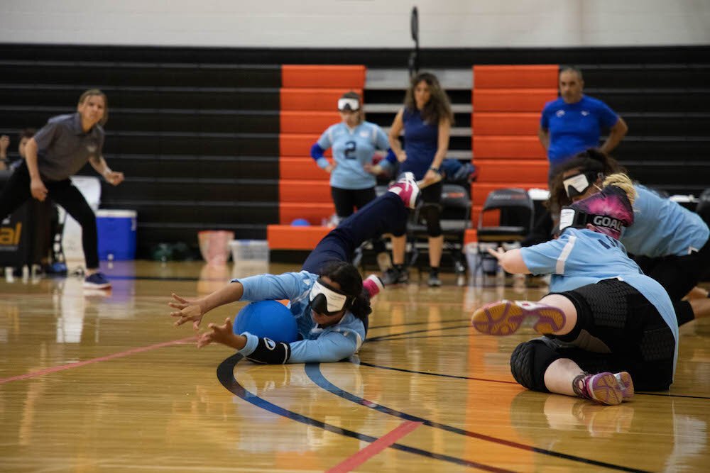 Goalball players block the ball from the opposing team.