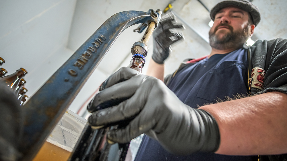 Drew Wilks caps bottles of beer at HopLore Brewing.