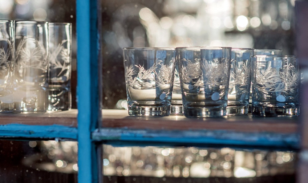 Hand-cut glass tumblers rest on a shelf at Warsaw Cut Glass.
