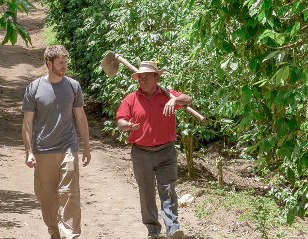 Maxwell, left, meets with farmers overseas.