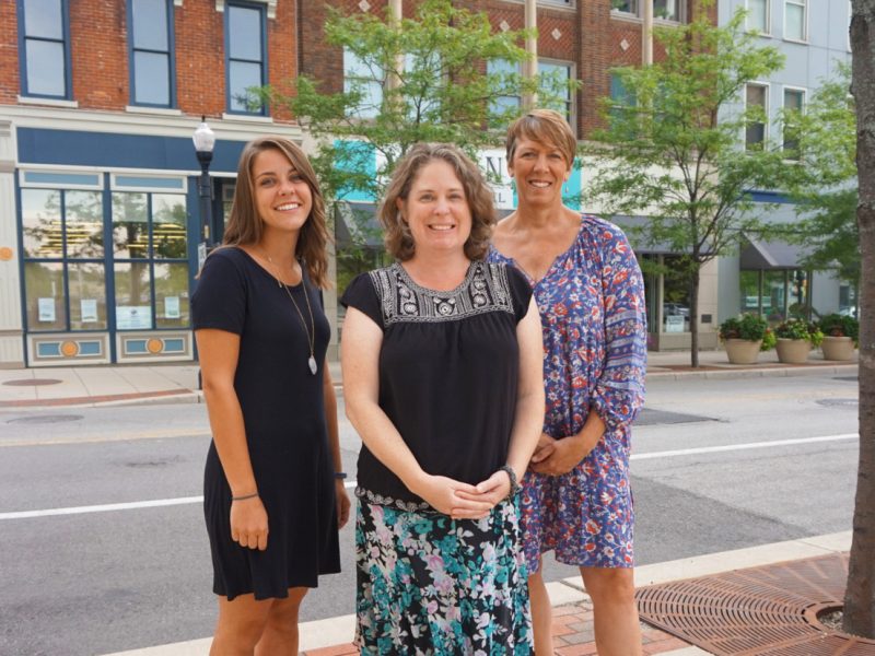 Aubrie Tinsley (left), Sara Gensic (center), and Suzy Ulmer (right) in downtown Fort Wayne with the Alyssum Montessori School behind them on the left.