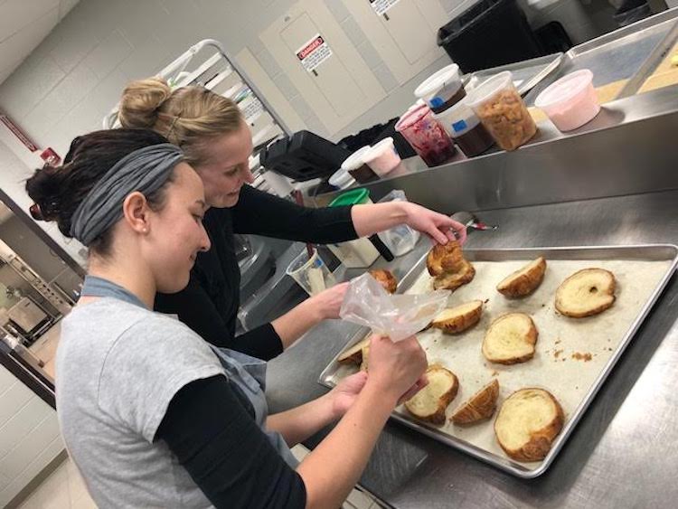 Makayla Coonce (front) and Hetty Arts put the final touches of frangiapanne filling on their croissants.