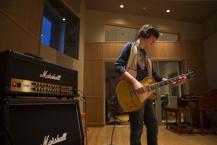 A Rock Camp student tests a guitar.
