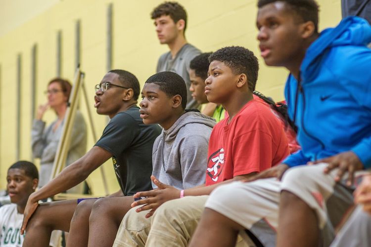 Participants in the Fort Wayne United Late Night Basketball Program wait on the bench during a game.