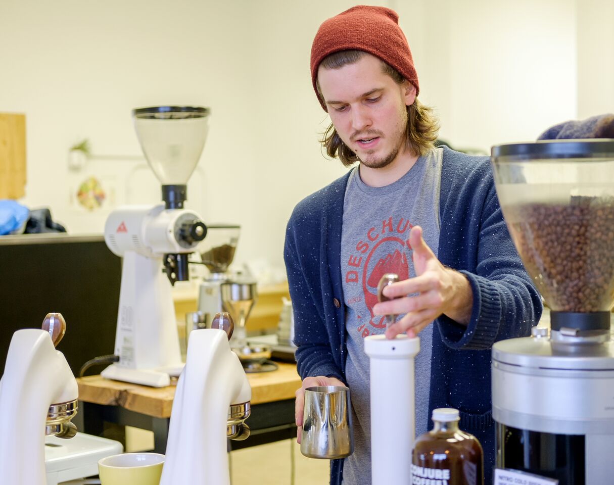 Drew Getz works behind the sleek Modbar setup at Conjure Coffee.