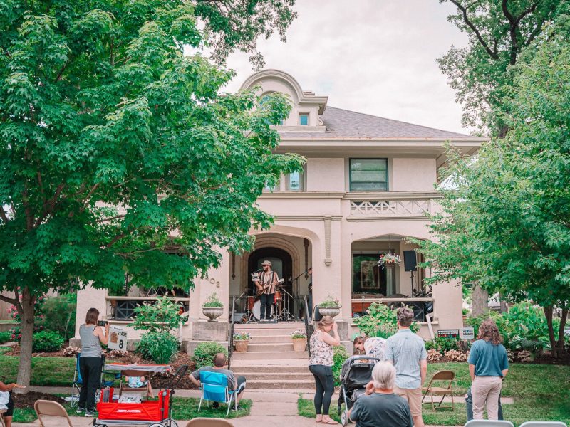 People gather to watch live music on a Williams Woodland Park front porch.