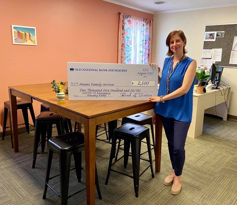 Amani Executive Director Irene Paxia poses with a check that represents a donation to the emergency relief fund.