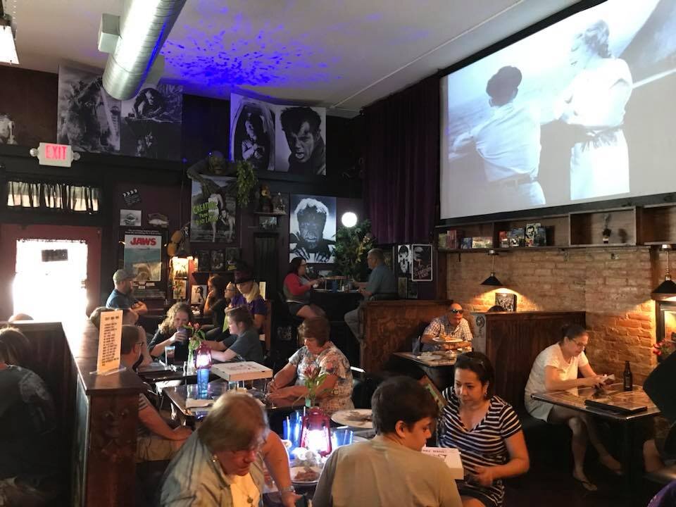 Famous Monster Pizza shows classic horror films as patrons eat.