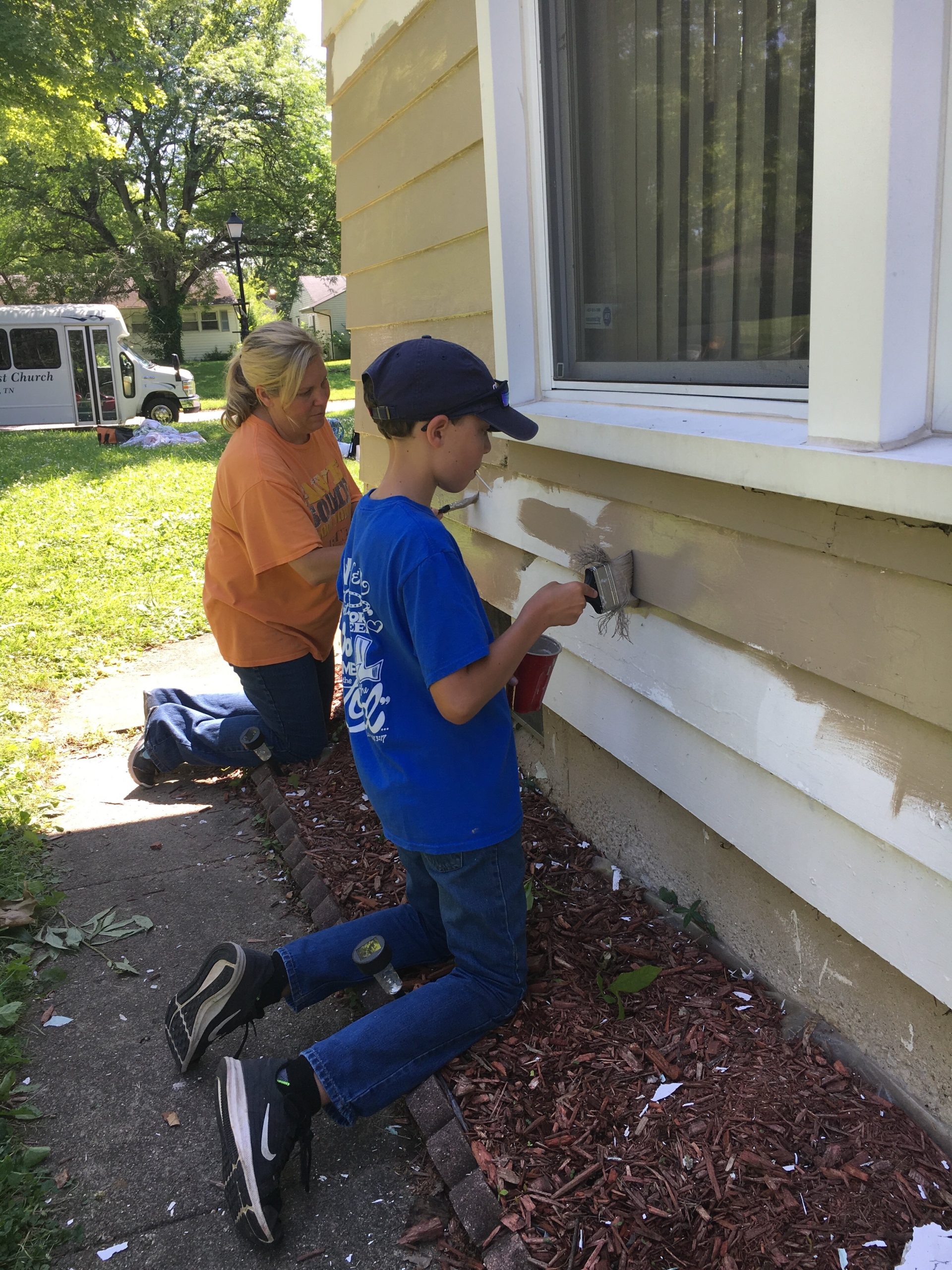 NeighborLink Fort Wayne volunteers paint siding.