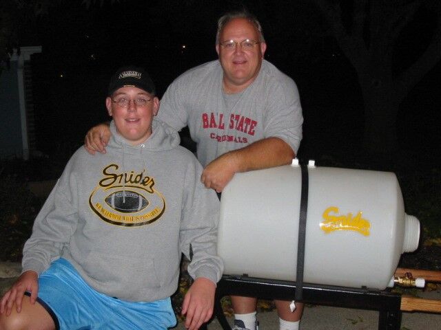 Greg Parks, right, and his son Steve, left, next to the first water cart they built together for the Snider football team.
