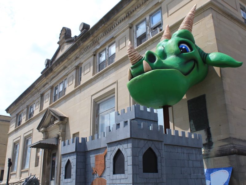 Charlie, the gigantic green dragon, welcomes customers to TCB Games.