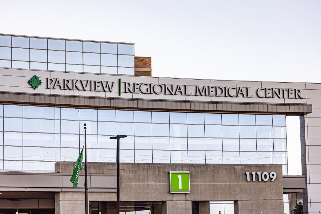 A large grey and brown hospital with big windows and a sign in white lettering that reads, "Parkview Regional Medical Center".