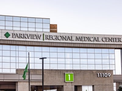 A large grey and brown hospital with big windows and a sign in white lettering that reads, "Parkview Regional Medical Center".